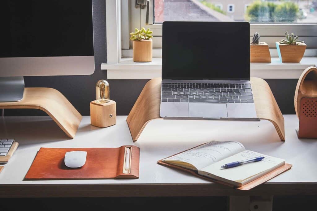 Mesa com computador, mouse e caderno