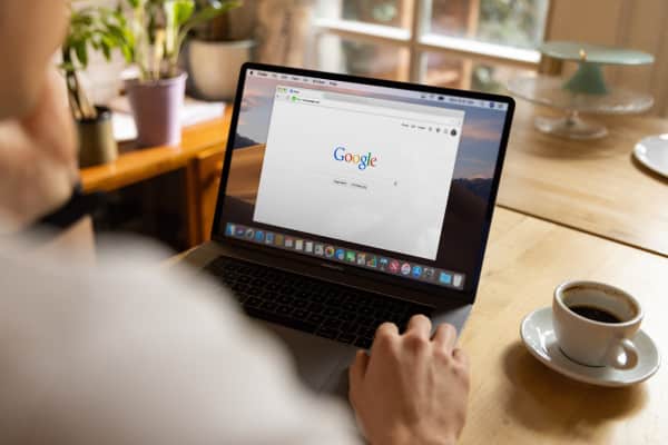 Uma pessoa trabalhando com a aba do Google em uma mesa com um café.