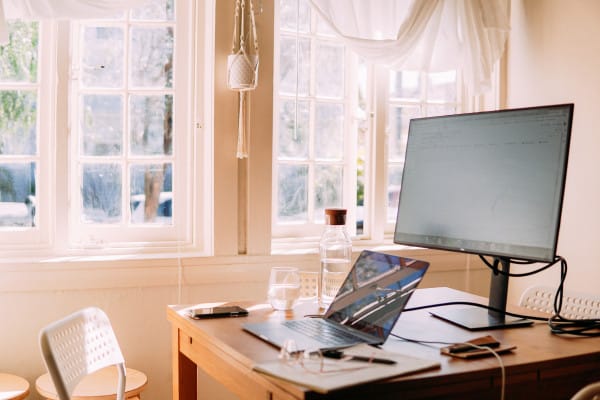 Mesa com um notebook e um monitor de apoio.