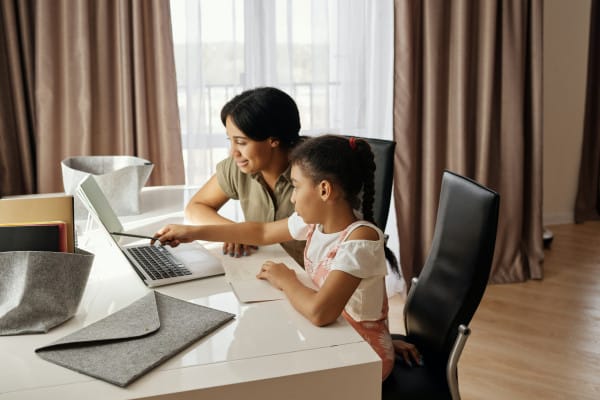 Uma pessoa adulta e uma criança olhando para um computador.