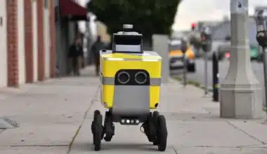 Robô-entregador na calçada de uma grande cidade