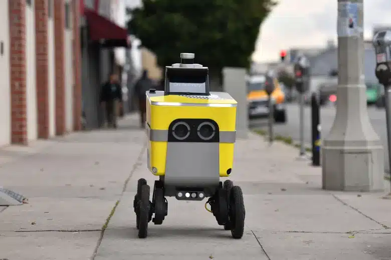 Robô-entregador na calçada de uma grande cidade
