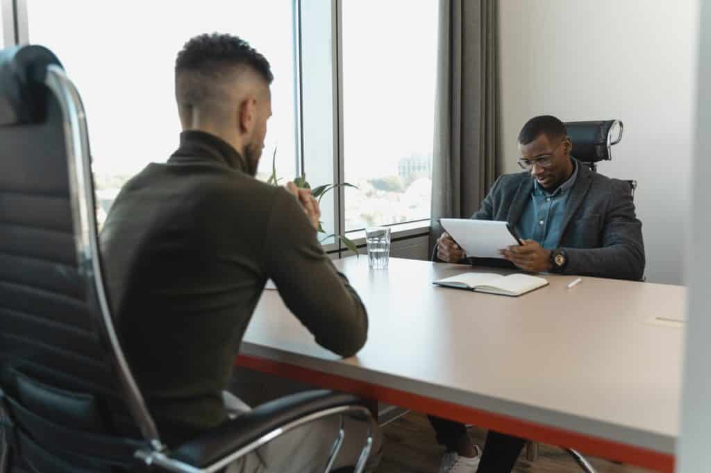 Duas pessoas sentadas em uma mesa de reunião em um ambiente organizacional dando feedback positivo. 