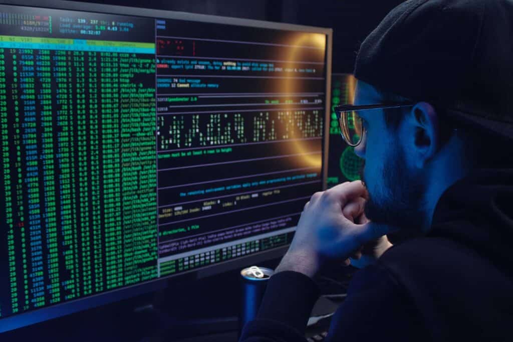 homem olha para tela do computador com códigos hackers