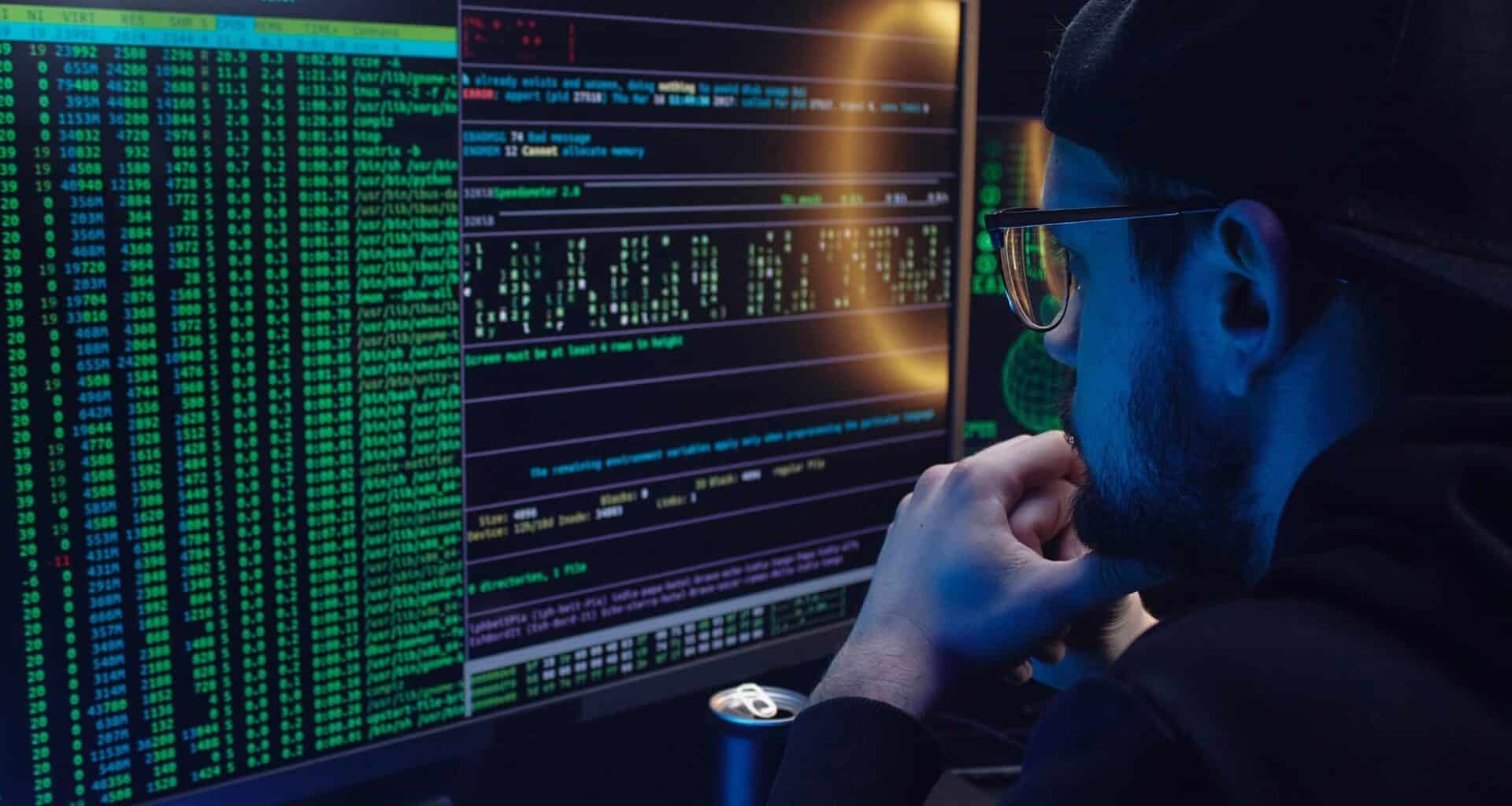 homem olha para tela do computador com códigos hackers