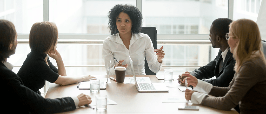 Mulher preta na posição de liderança, conduzindo uma reunião