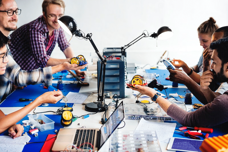 Trabalhar com tecnologia, uma mesa de pessoas desenvolvendo máquinas com diversas peças